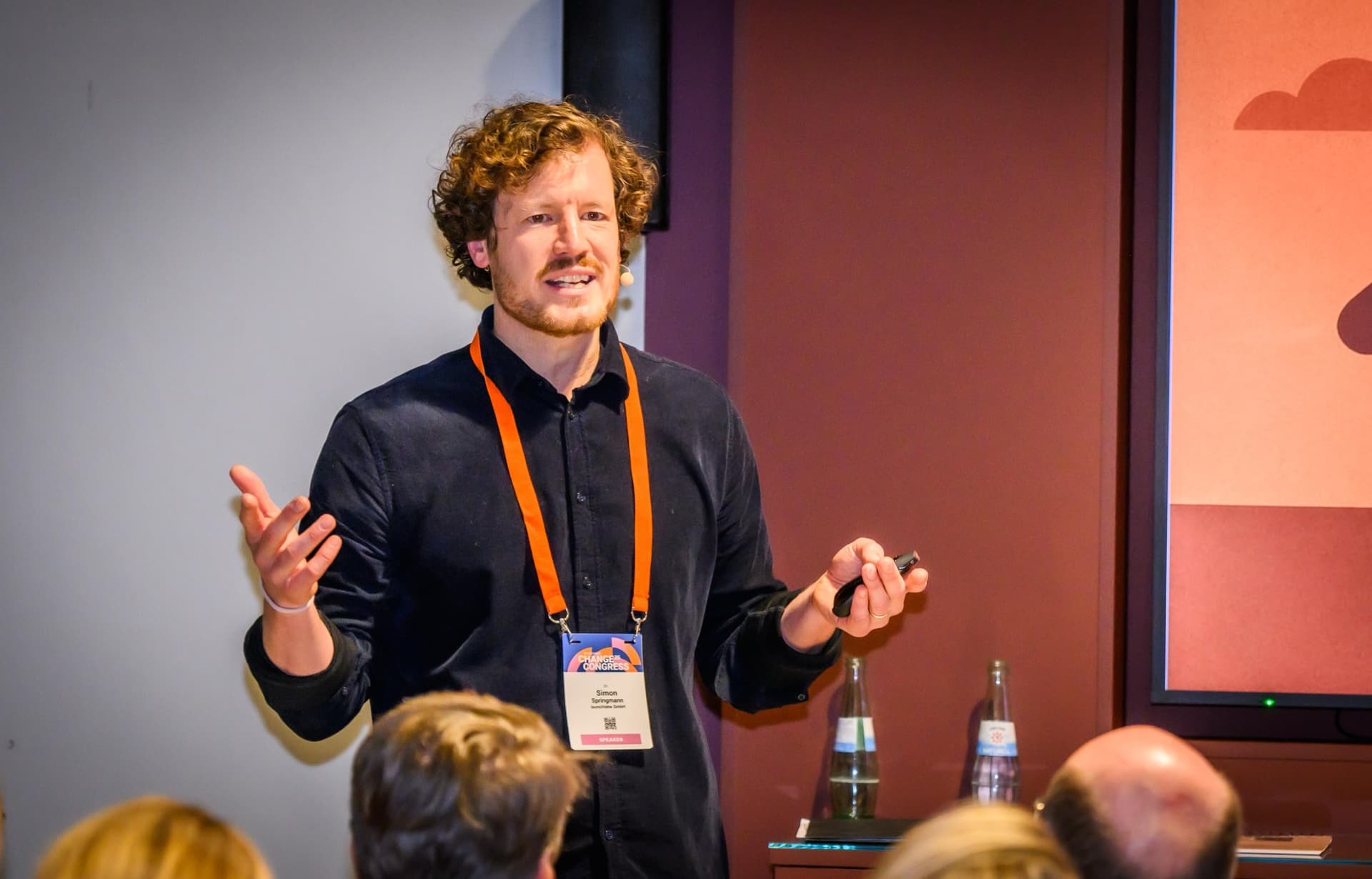 Dr. Simon Springmann auf der Bühne mit Headset-Mikrofon, gestikulierend während eines Vortrags auf dem Handelsblatt Change Congress 2025 in Berlin