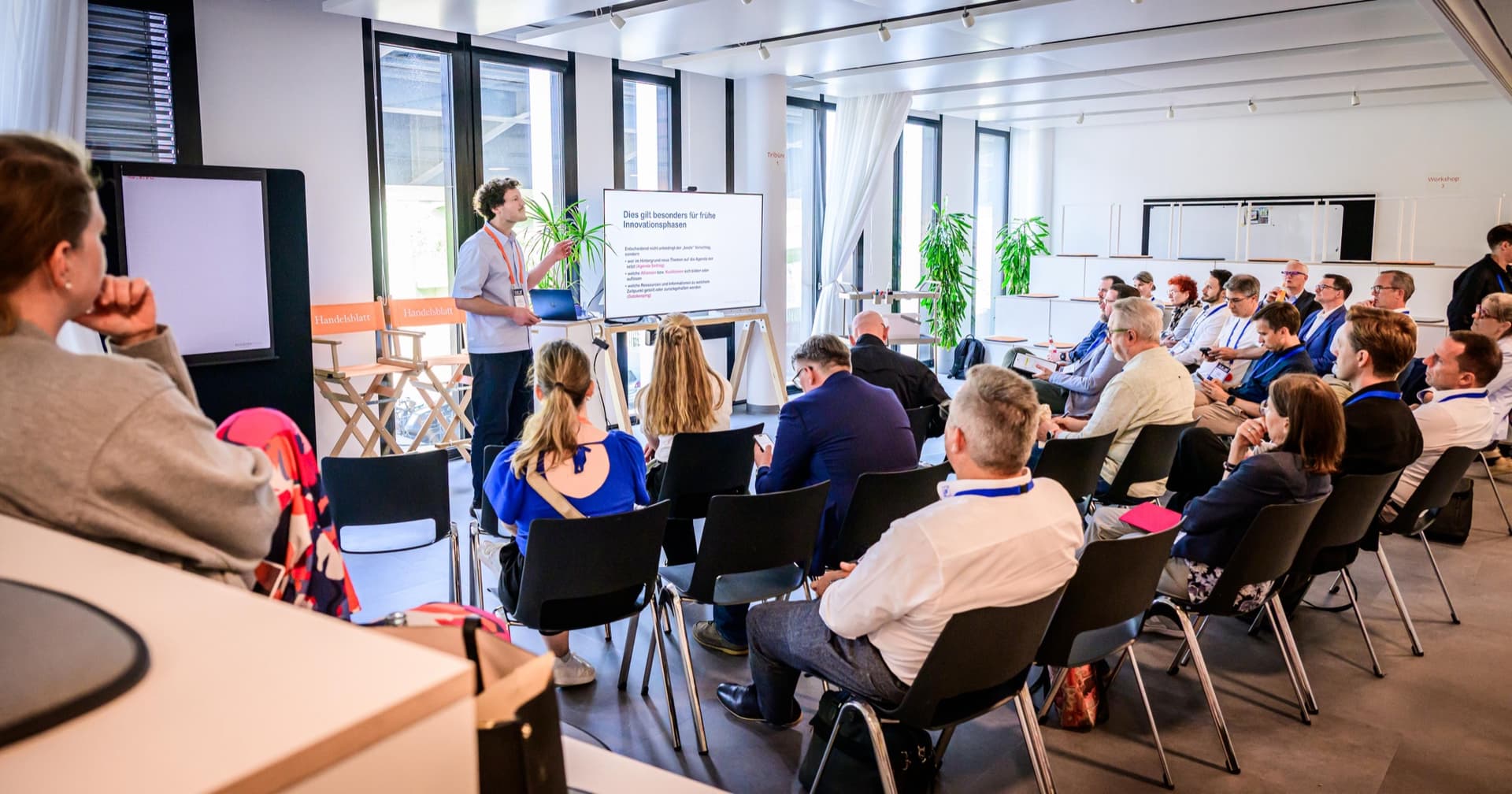 Voll besetzter Raum bei der Masterclass „Micropolitics eats KI-Strategy for Breakfast“ auf dem Handelsblatt Work in Progress 2026: Publikum von hinten, Dr. Simon Springmann vorne am Screen mit einer Slide zu frühen Innovationsphasen