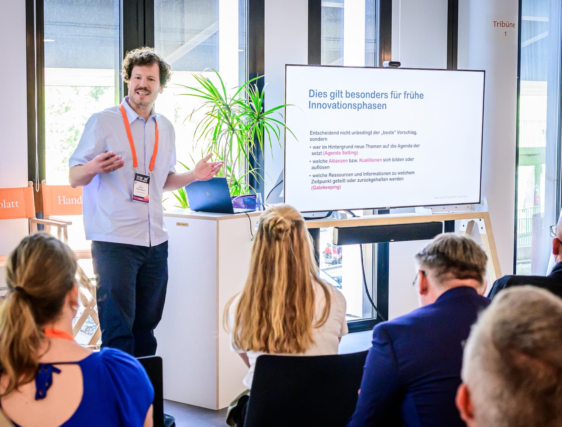 Dr. Simon Springmann gestikulierend während seiner Masterclass „Micropolitics eats KI-Strategy for Breakfast“ auf dem Handelsblatt Work in Progress 2026 in Berlin, vor einer Slide zu Mikropolitik in frühen Innovationsphasen